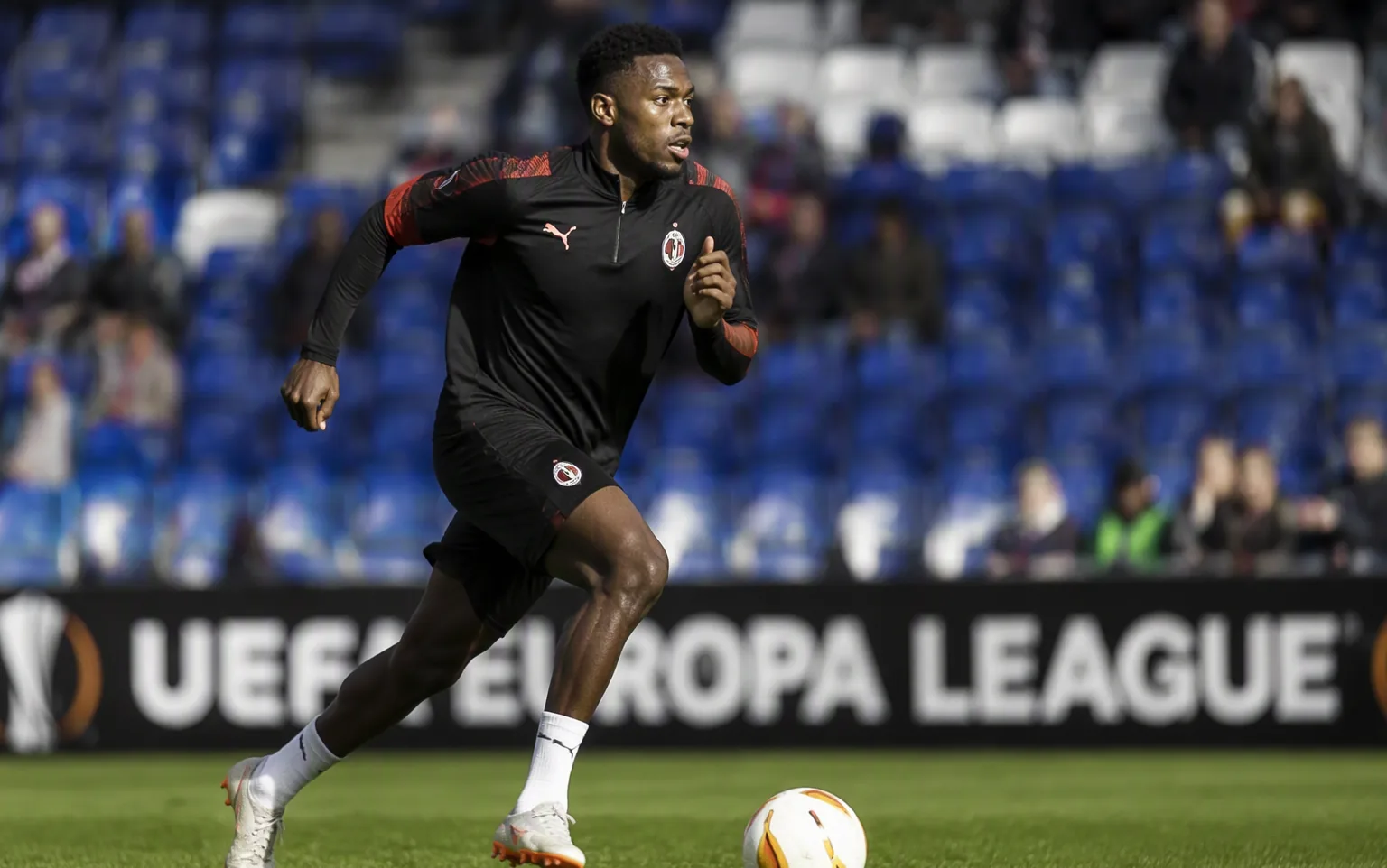 A footballer sprinting with the ball on a European pitch
