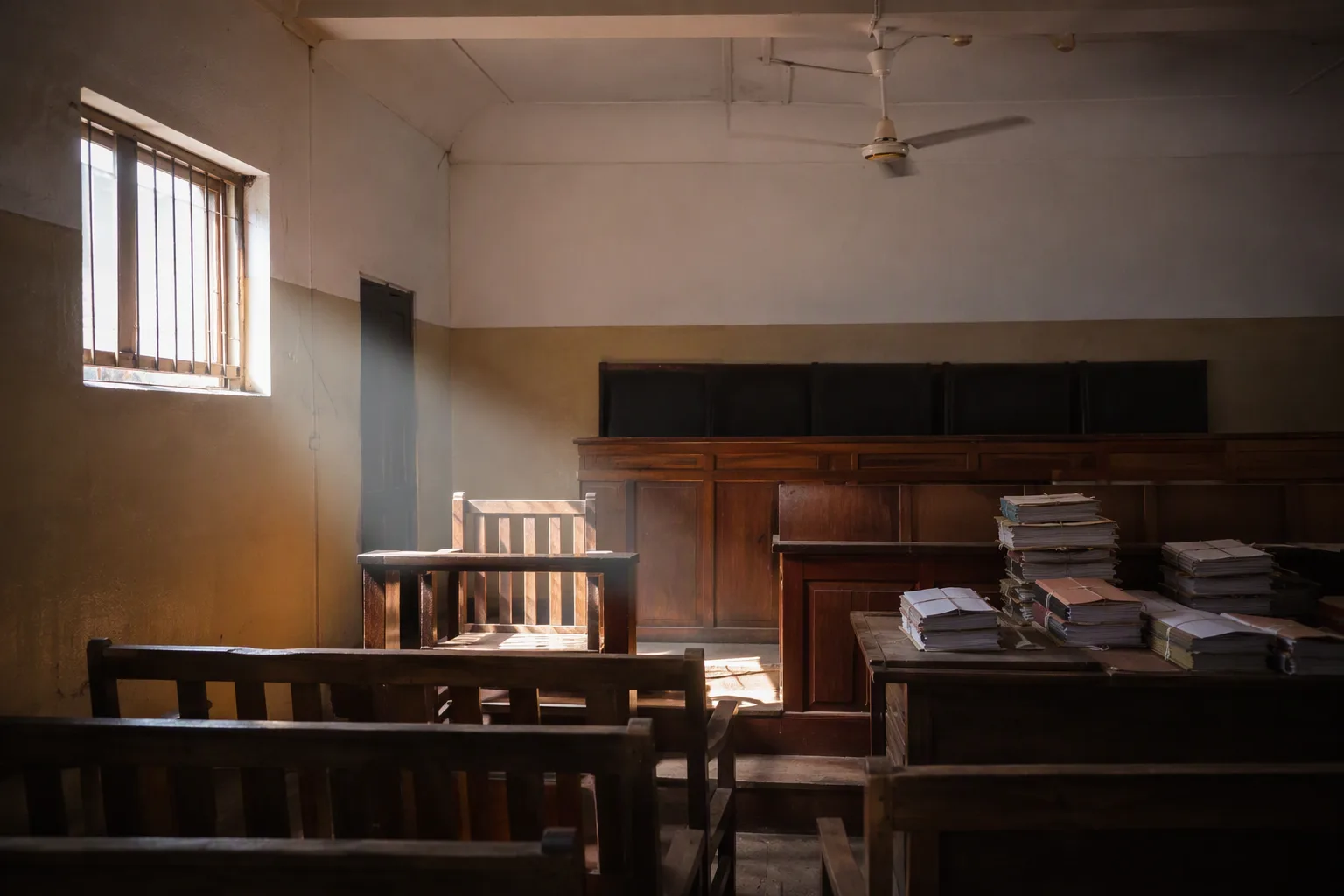 An empty witness chair in a shaft of light in a Chipata courtroom