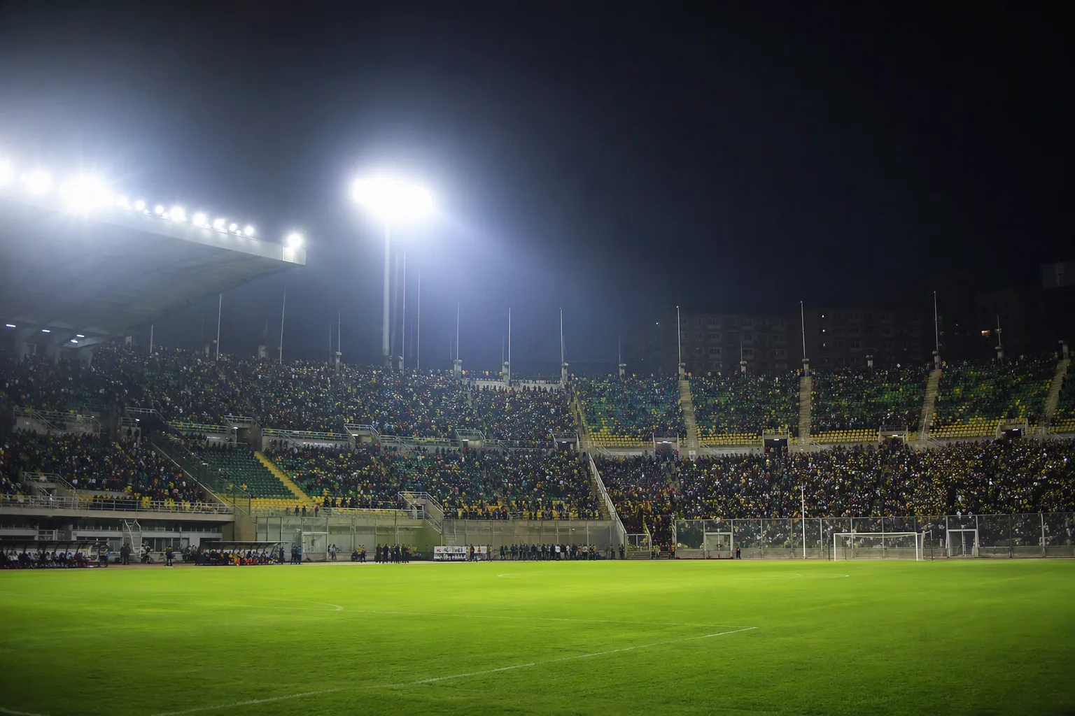 A large North African football stadium under floodlights at night