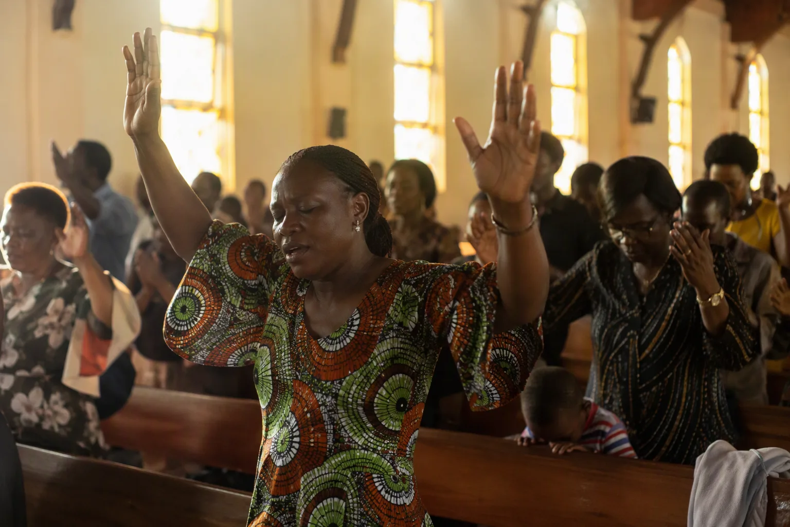 Congregants at a Lusaka church prayer service in soft window light
