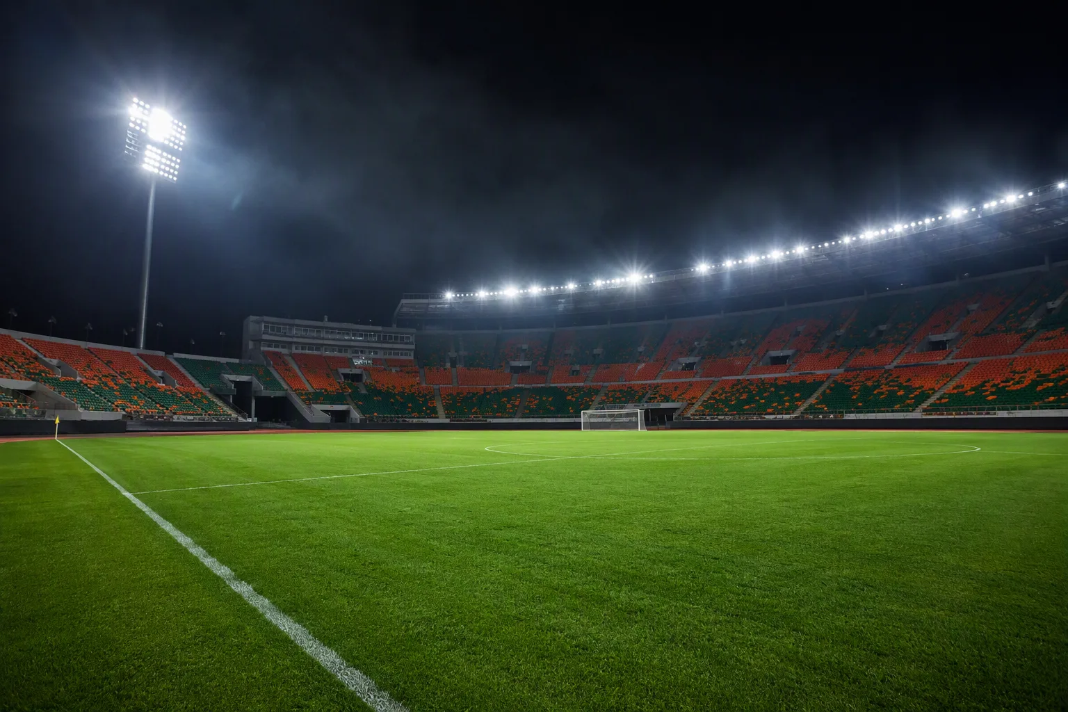 A floodlit football stadium at night with an immaculate empty pitch