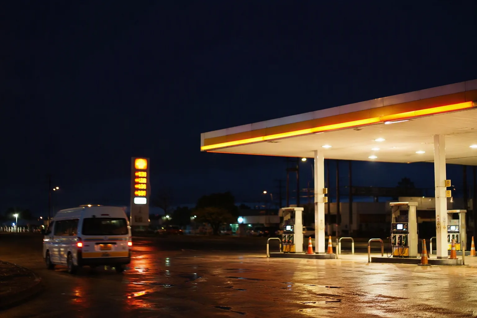 A quiet illuminated fuel station forecourt late at night with a minibus pulling away