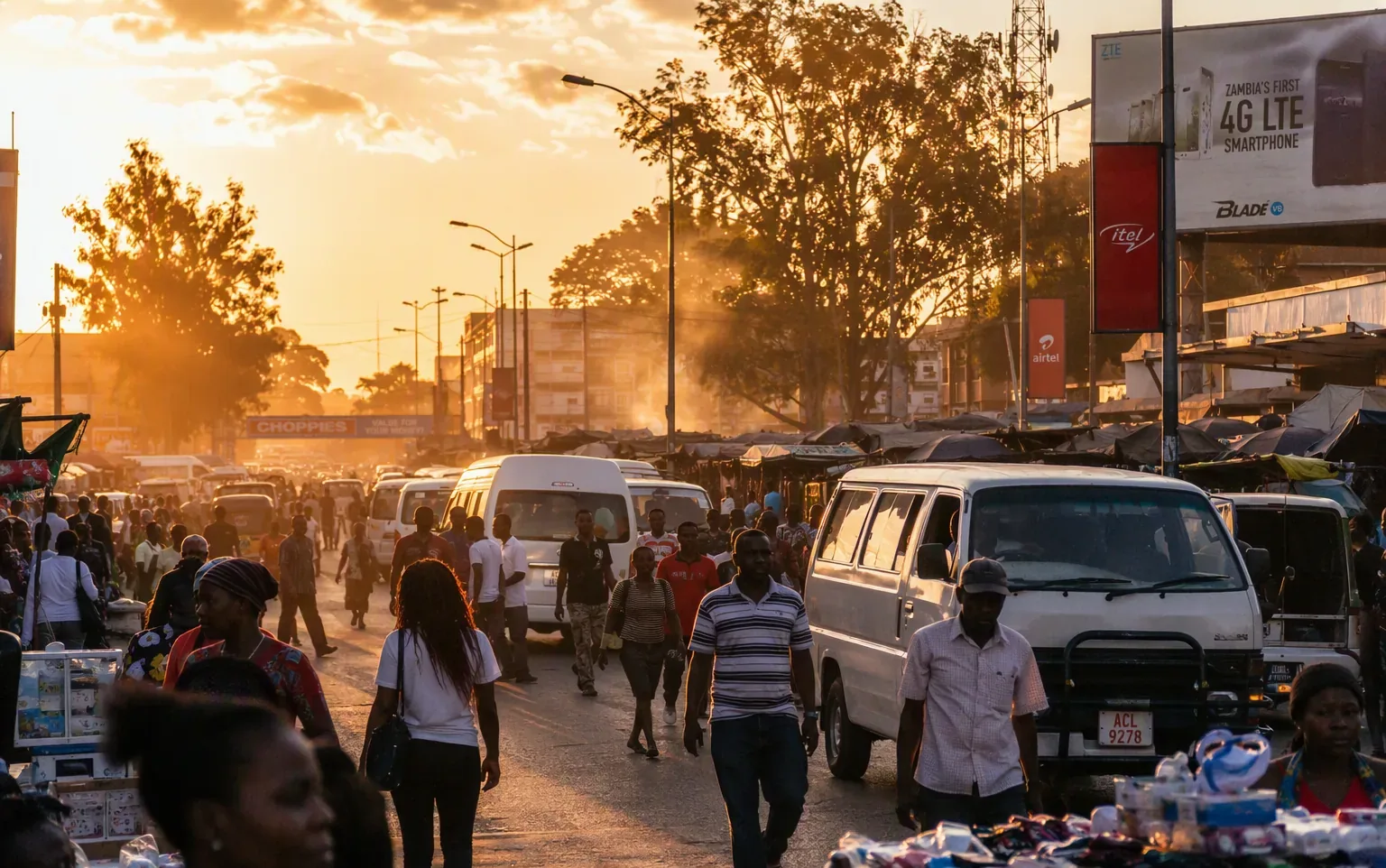 A Lusaka street at golden hour with minibuses and market vendors